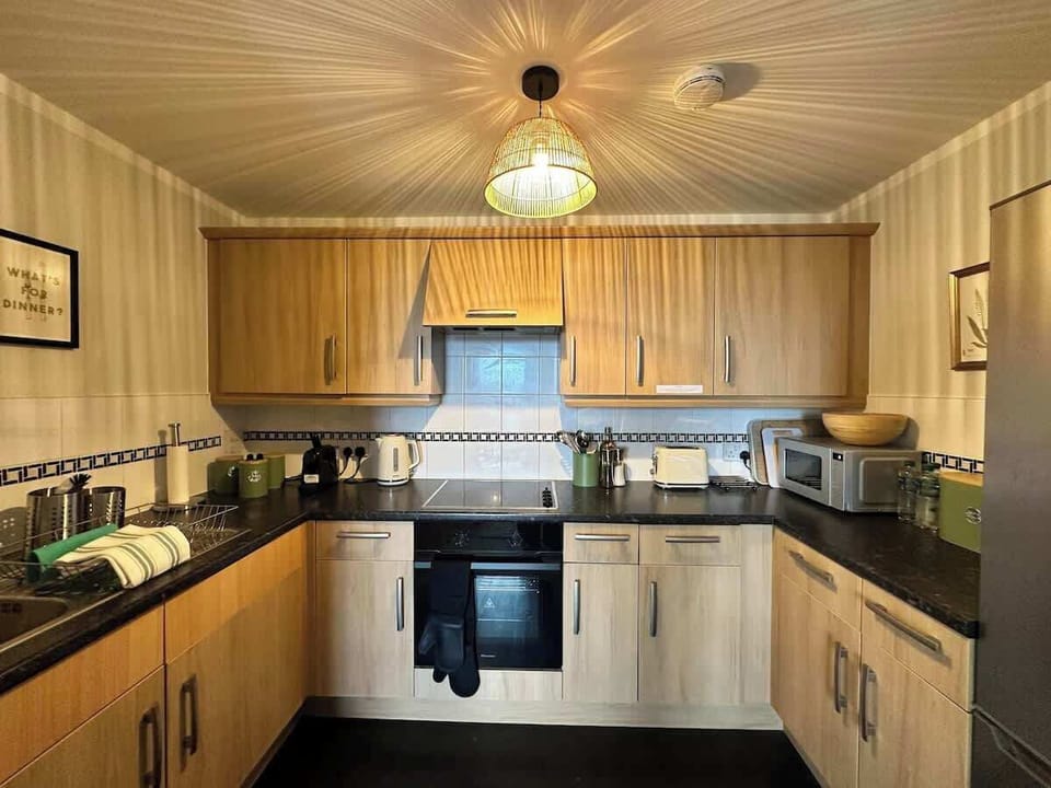 A fully equipped kitchen with sleek light wood cabinetry and dark granite-effect worktops. Everything you need for home cooking is here — including a built-in oven, ample storage, and generous counter space to make every meal a pleasure to prepare.