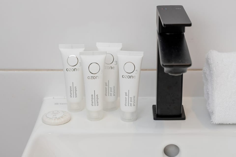 A close-up bathroom detail showing toiletries neatly arranged beside a modern black faucet. The styling gives the space a hotel-like feel.