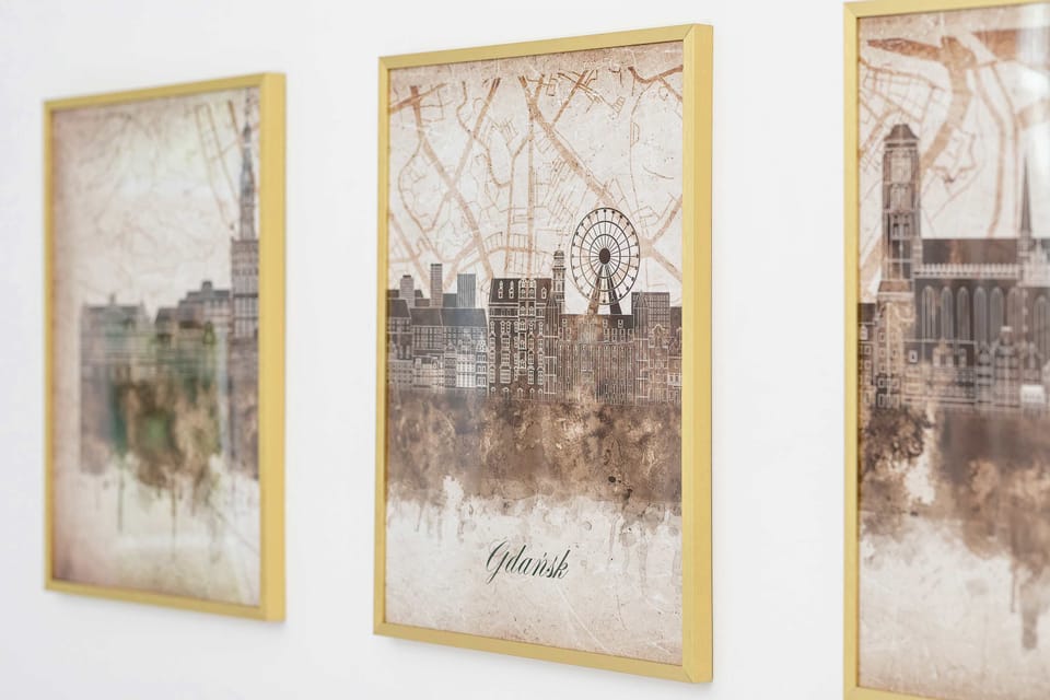 A decorative triptych of framed artwork featuring architectural sketches and muted earth tones. The pieces are mounted on a white wall as a focal point.