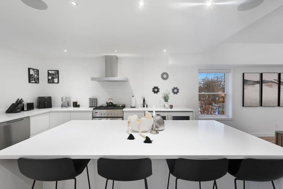 Modern, sleek kitchen with a large island, gas stove, dishwasher, coffee maker, toaster, and stylish decor accents.