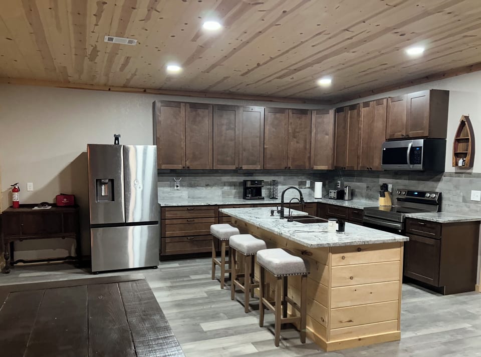 Stocked kitchen with electric oven/cooktop, microwave, barstools, and appliances