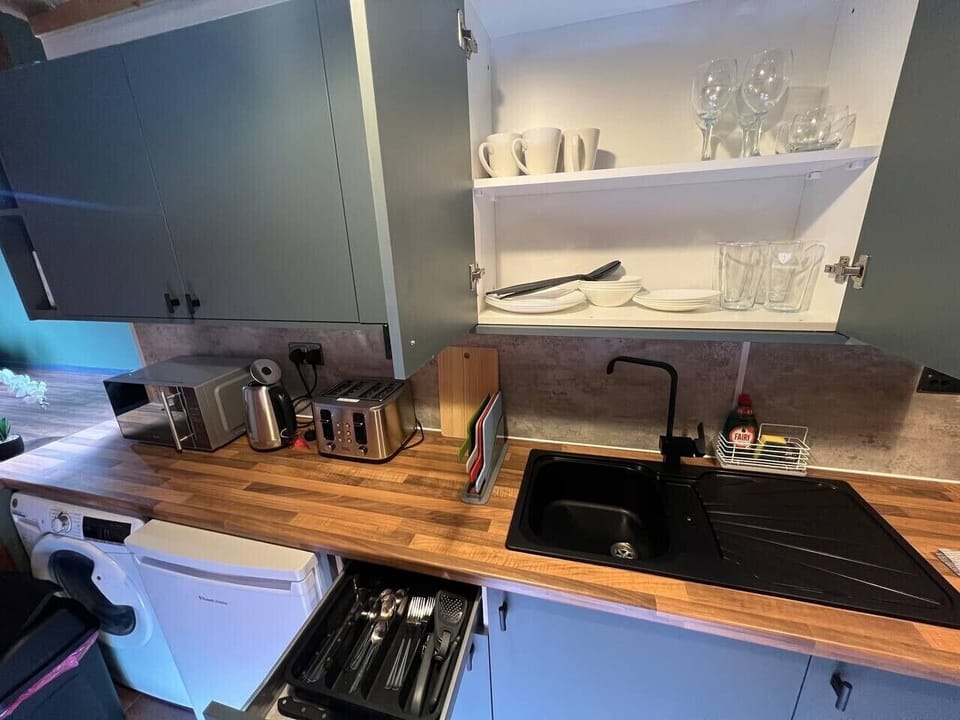 Fully equipped kitchen with oven, hob, microwave, kettle, toaster, fridge, and washing machine. Includes cookware, cutlery, plates, and glasses—everything needed for cooking and a comfortable stay in Liverpool city centre.