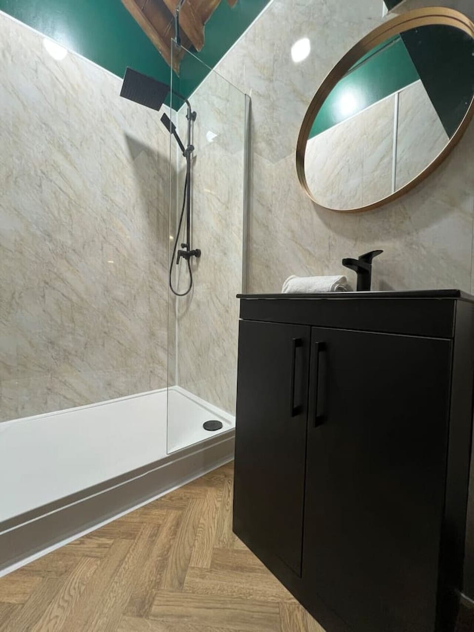 Modern bathroom with walk-in shower and sink, featuring stylish tiled walls, wooden flooring, and contemporary design. Clean, bright, and perfect for a comfortable stay in Liverpool city centre.