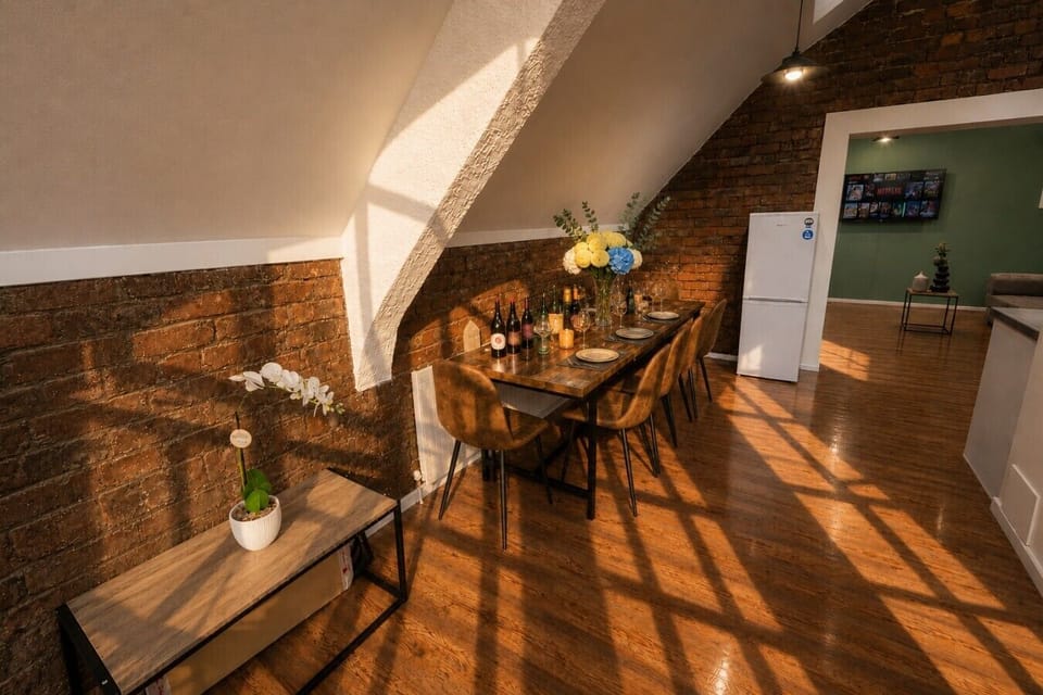 Dining area with seating for your group, set beside the apartment’s original exposed brickwork and filled with natural light.