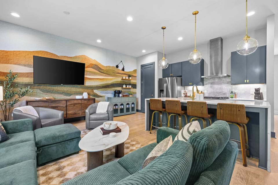 The mural wall, kitchen, and living space all connect on the main floor. Gold pendant lighting keeps the whole level feeling cohesive.