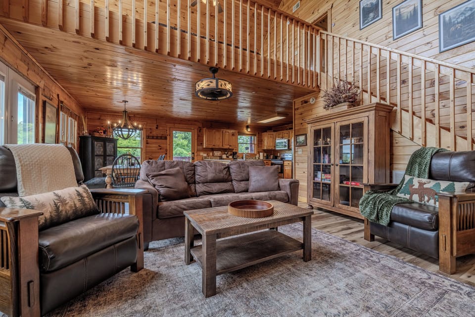 Open-concept living area with comfortable seating, a fully equipped kitchen, and warm cabin charm.