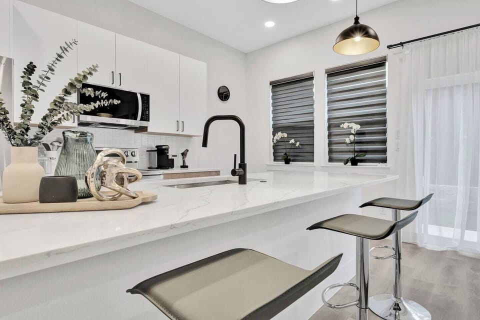 Modern fully equipped kitchen with stainless-steel appliances, bar seating, and spacious countertops—perfect for coffee, home-cooked meals, or late-night snacks.