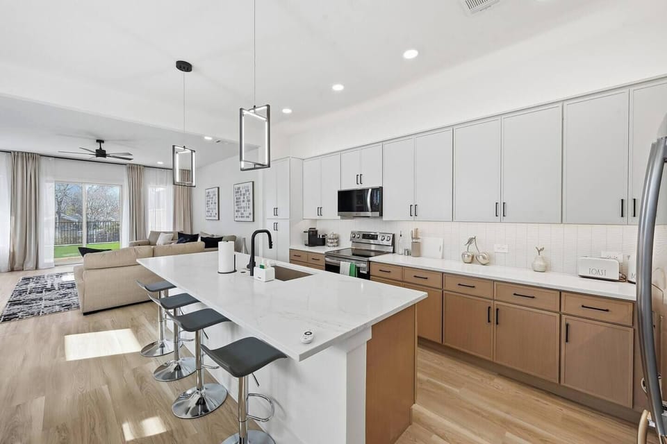 Spacious full kitchen with oversized island, quartz countertops, stainless steel appliances, and bar seating. Fully equipped for cooking and entertaining, with open flow into dining and living areas.
