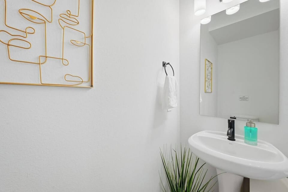 Convenient half bathroom on the main level with modern pedestal sink, sleek fixtures, and stylish décor. Perfect for guests and added comfort during your stay.