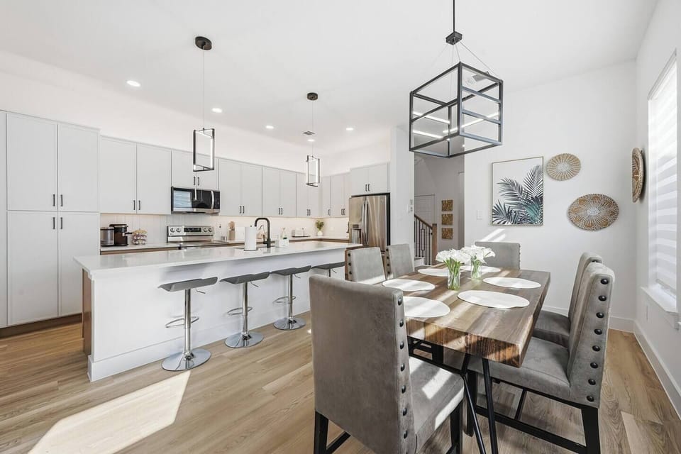 Bright dining area with seating for six, modern lighting, and large windows that fill the space with natural light. Perfect for family meals or group gatherings.