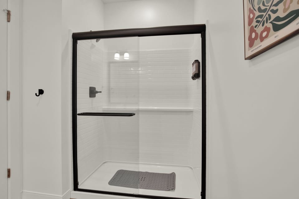 Bright modern walk-in shower with sleek glass doors and stylish black trim
