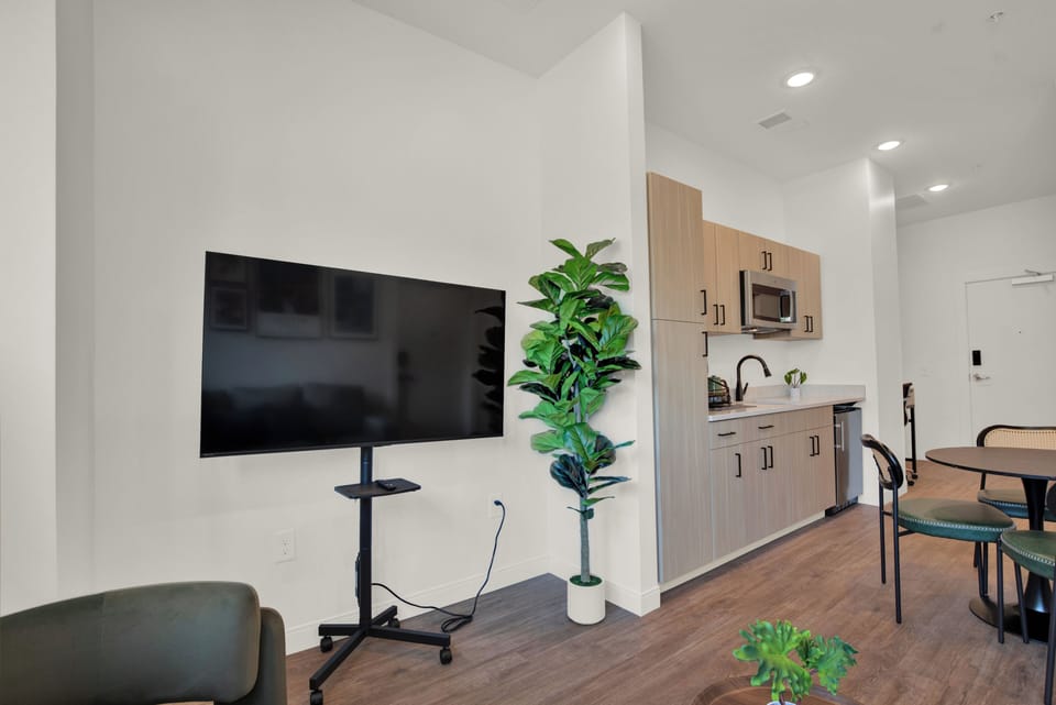 Bright modern studio with kitchenette, dining area, and large TV