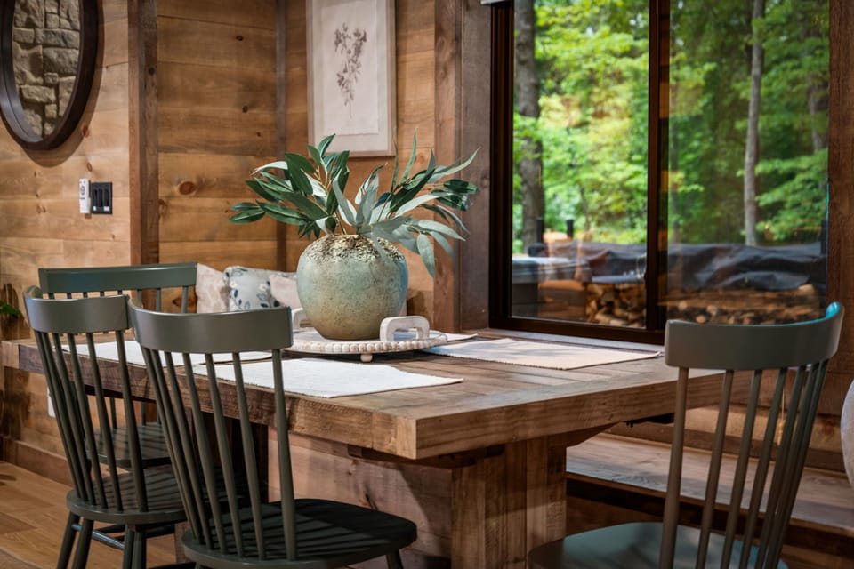 Rich green chairs echo the forest beyond the windows, while natural textures and carefully curated details bring warmth, character, and a sense of connection to nature.