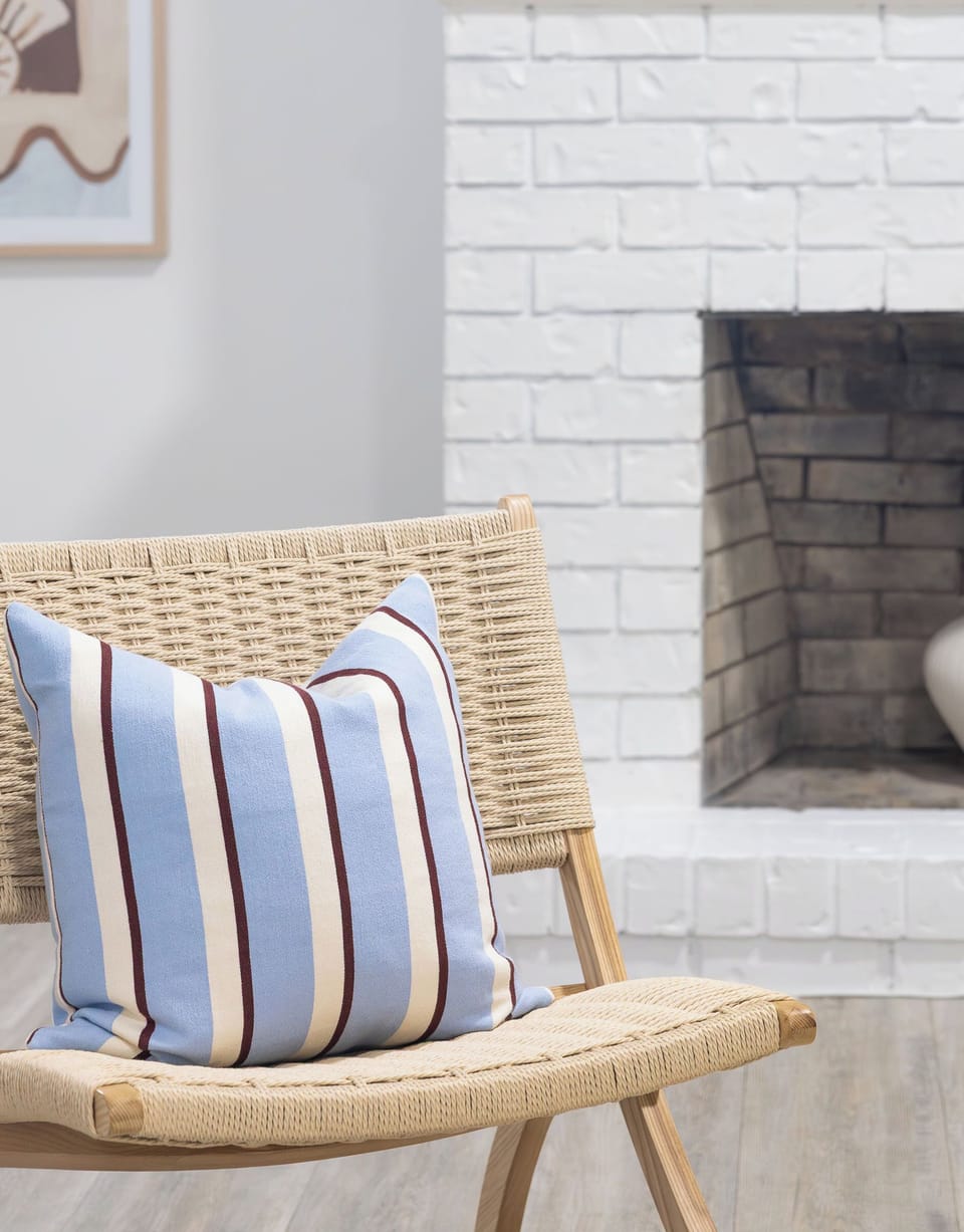 Cozy woven accent chair beside a bright white brick fireplace