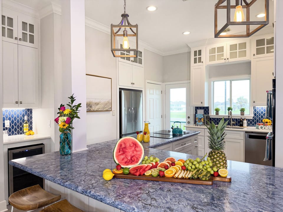 Large gourmet kitchen with oversized island, pendant lighting, and open-concept layout ideal for entertaining during beach vacations.