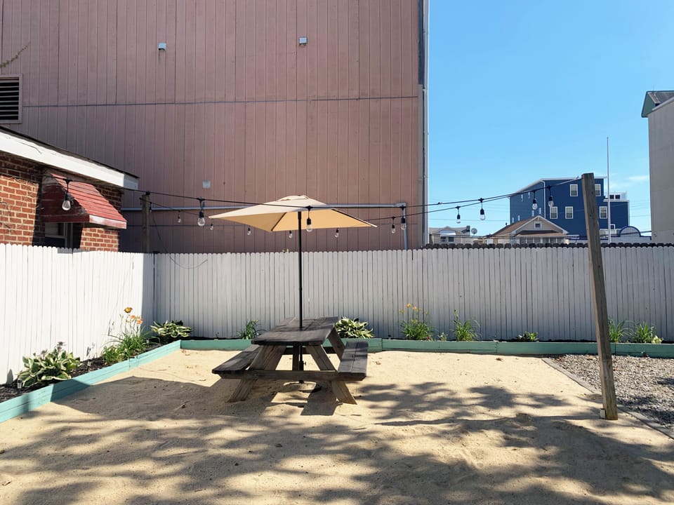 Private outdoor courtyard with picnic table, shade umbrella & string lights