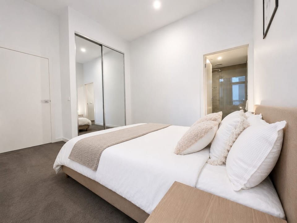Bright modern bedroom with mirrored wardrobes and ensuite access
