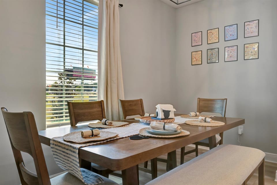 Six-seat dining table positioned beside backyard-facing windows