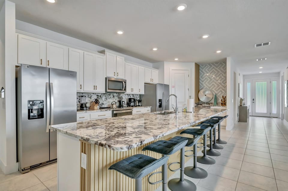 Open layout kitchen with stainless steel appliances and two double-door fridges with purified water dispensers and ice makers