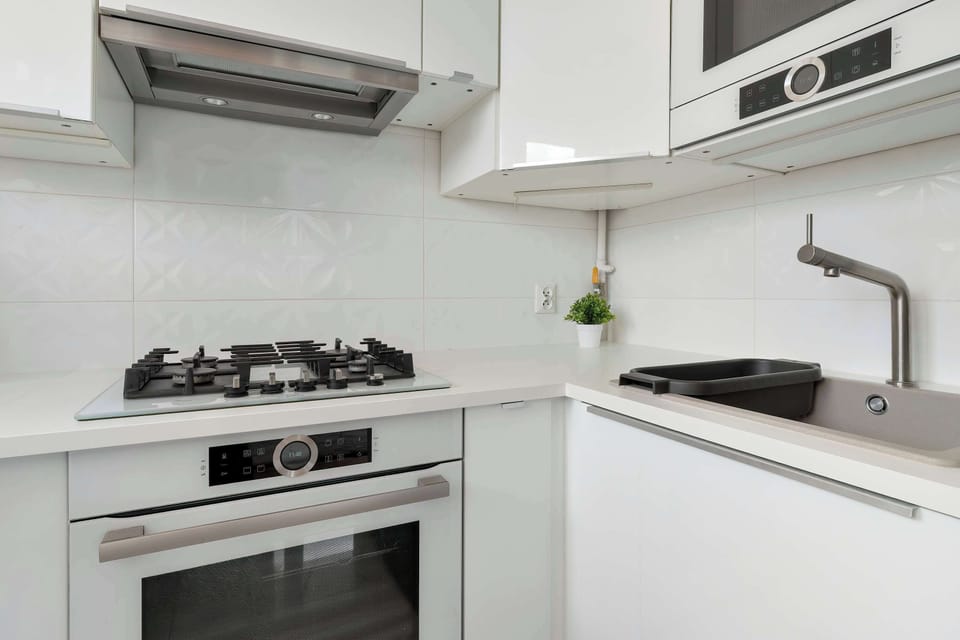 A kitchen perspective highlighting the cooking area, white cabinetry, and wall-mounted air-conditioning unit above.