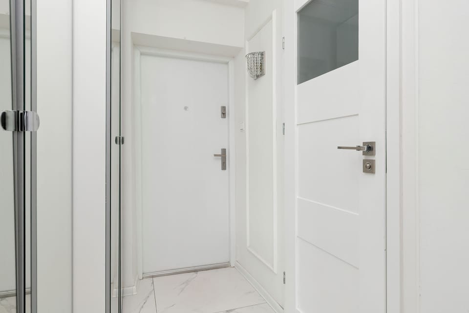 A minimalist entrance hallway with white doors, light-colored walls, and simple modern finishes.