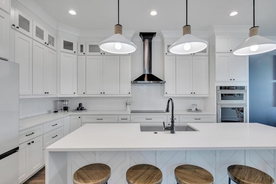 Gather around the spacious island and feel at home in this bright, chef-ready kitchen with gleaming countertops and warm pendant lighting overhead.