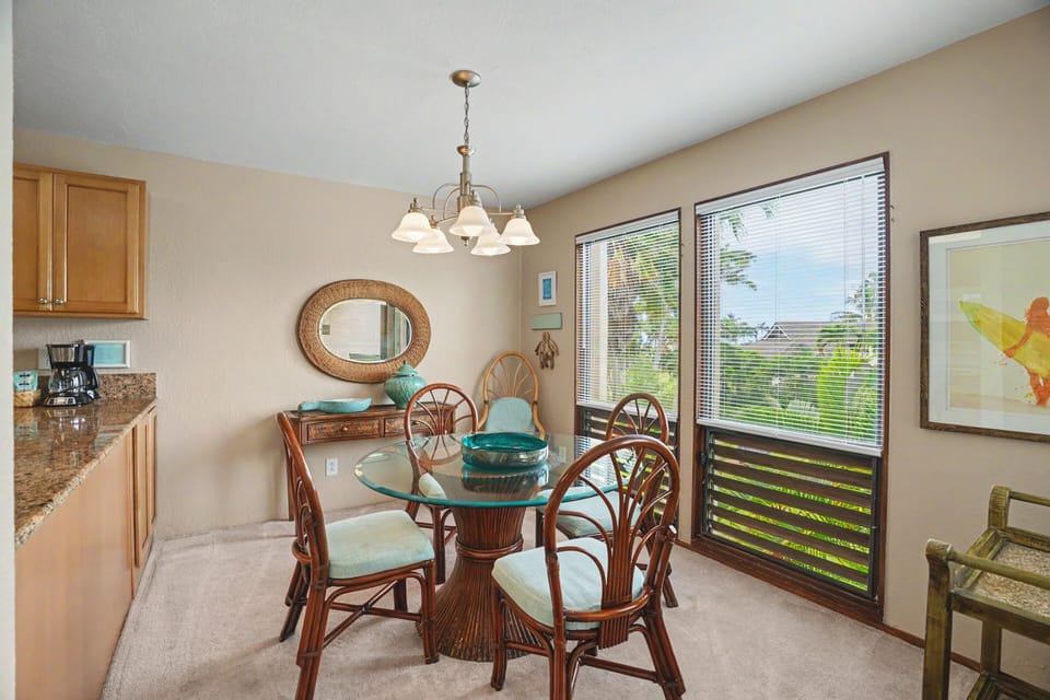 Gather around the tropical-style dining table where natural light streams through large windows. You'll love sharing meals in this bright, cheerful space with island-inspired décor and garden views.