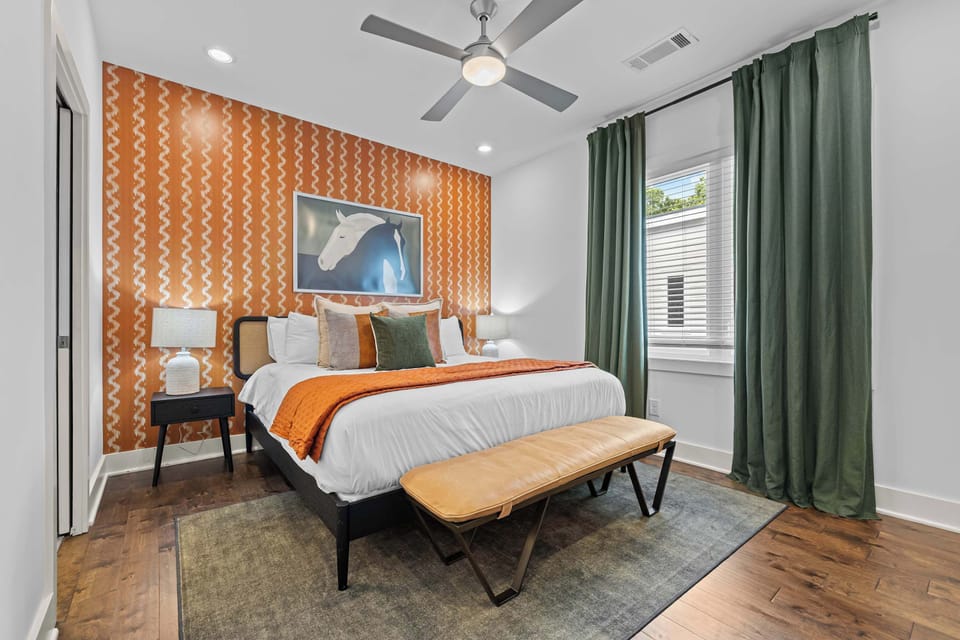 Primary suite featuring a king bed, statement wallpaper, and blackout curtains