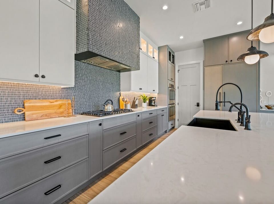 You'll love preparing meals in this sleek, modern kitchen with its stylish mosaic tile backsplash, ample counter space, and fully equipped appliances ready for your culinary adventures.