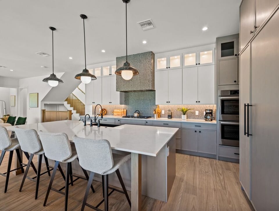 Gather around this spacious island in your chef-inspired kitchen, where sleek pendant lights illuminate your meal prep and custom cabinetry keeps everything at your fingertips.