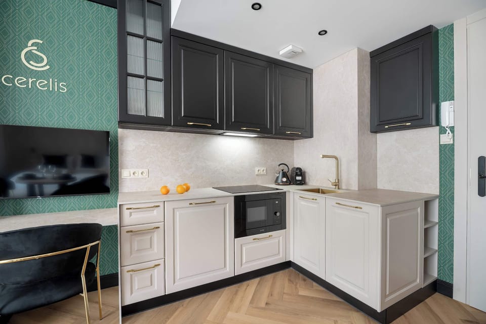 A stylish, dark-themed kitchenette equipped with modern appliances and glossy black cabinetry. A functional countertop offers ample space for meal preparation in this compact, well-designed layout.