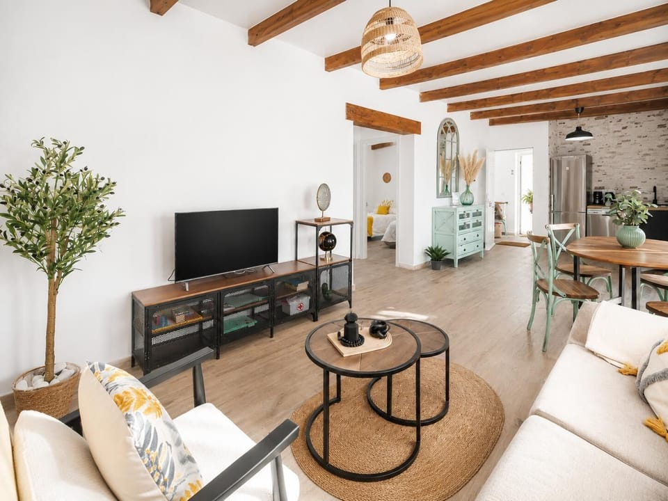 Bright open-plan living and dining area with wooden beams, natural decor, and a stylish modern kitchen.