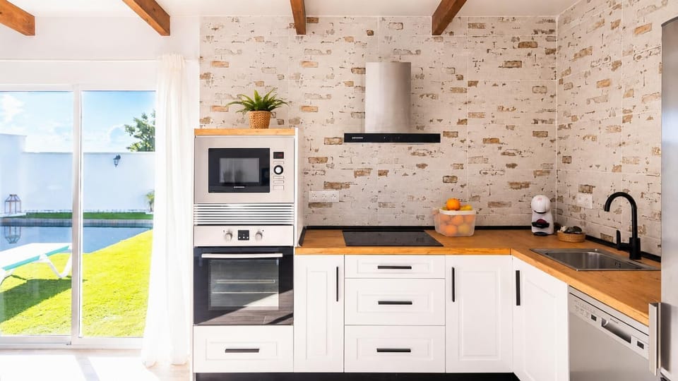 A bright modern kitchen with pool views and warm wooden countertops.