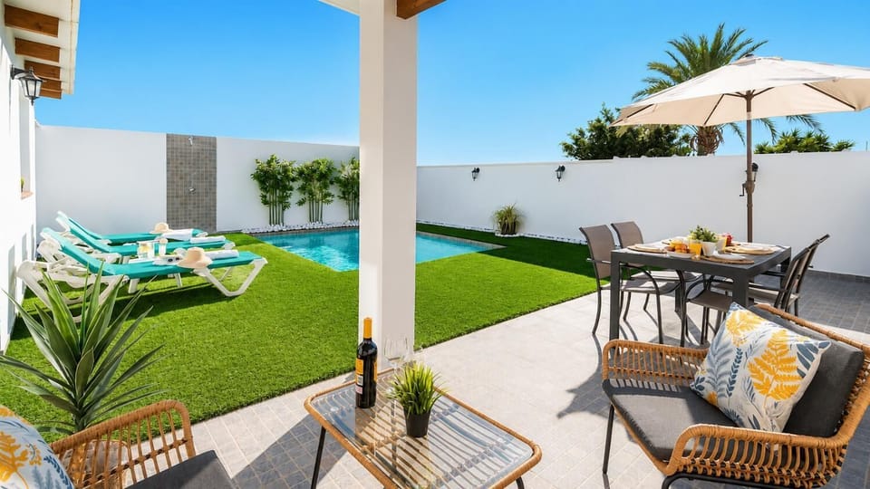 A stylish private pool terrace with sun loungers, shaded seating, and outdoor dining.