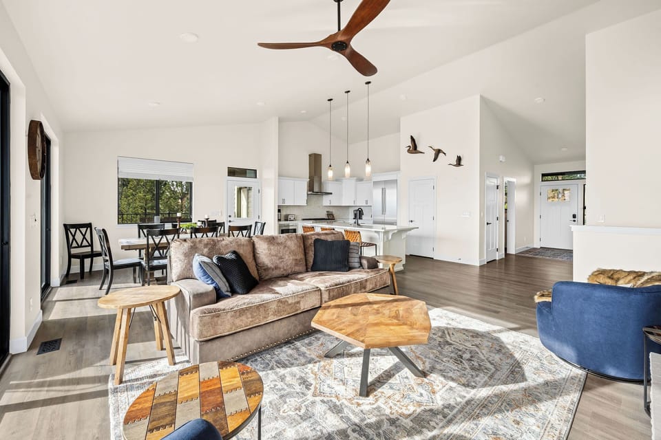 Step into an open-concept living space where modern comfort meets warm elegance. Natural light fills the room, highlighting the vaulted ceilings, rich wood accents, and inviting seating areas.