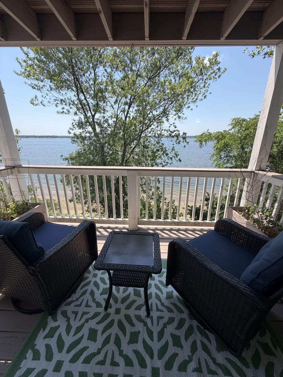 Private covered balcony with cozy seating and serene waterfront views