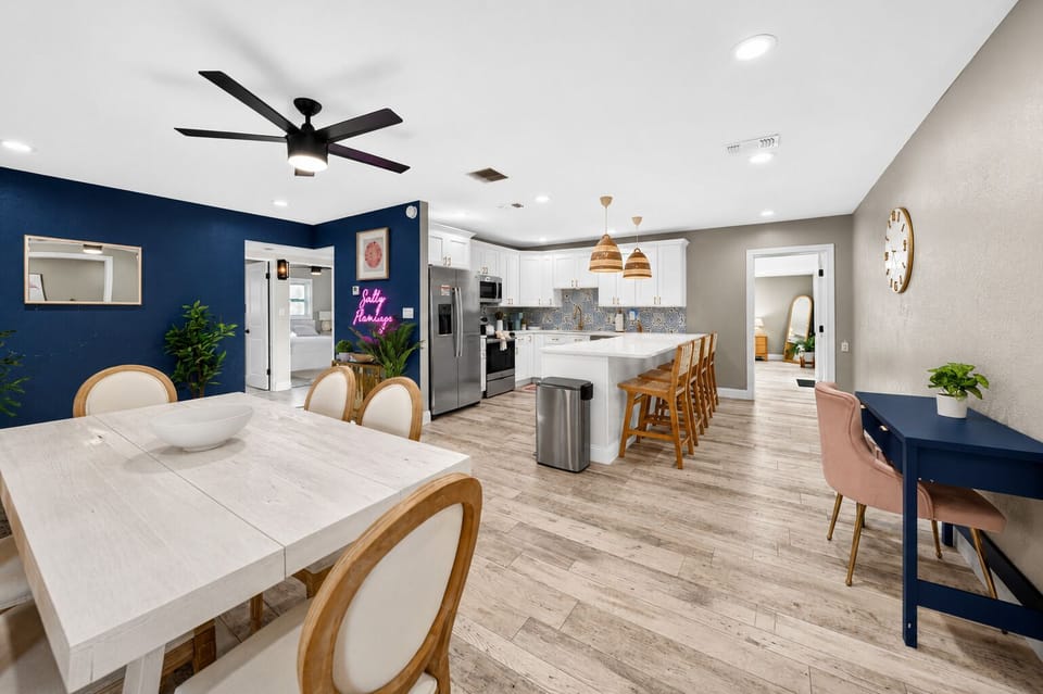 Open dining and kitchen space with a large dining table, breakfast bar seating, pendant lighting, and contemporary finishes.