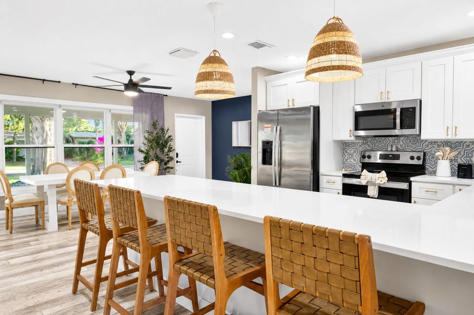 Gourmet kitchen with expansive island seating, woven pendant lighting, stainless steel appliances, and open entertaining space.