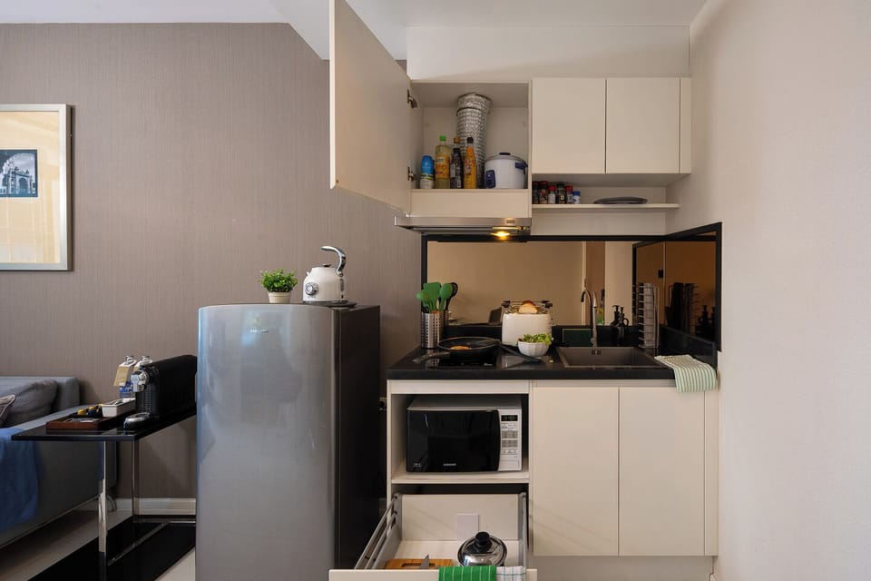 Compact modern kitchenette with fridge, stove, sink, and microwave
