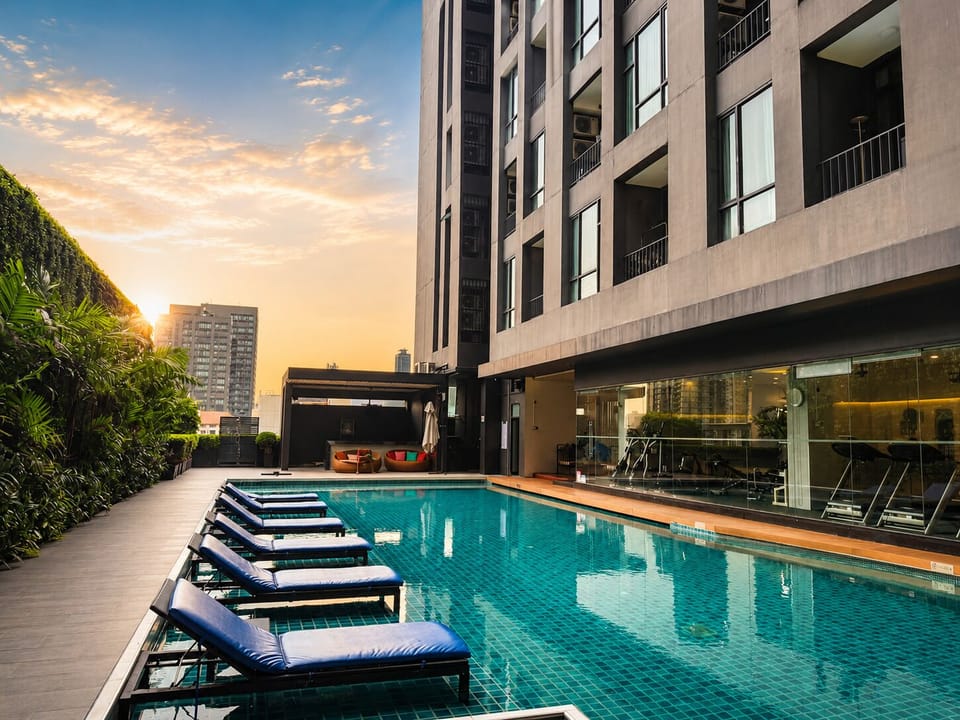 Modern city pool with in-water loungers, gym access, and sunset ambiance