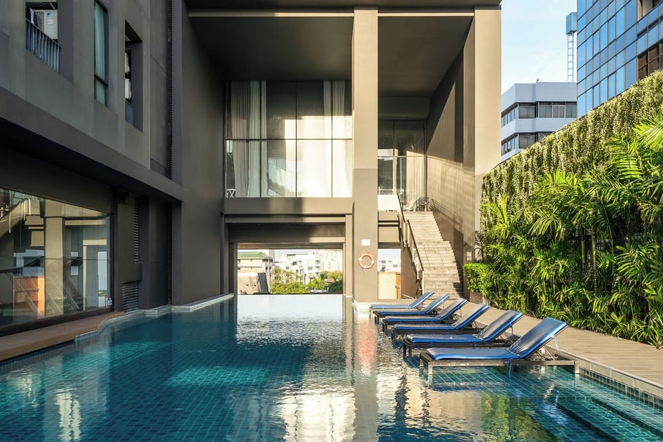 Stylish city pool with in-water loungers and a lush, resort-like vibe