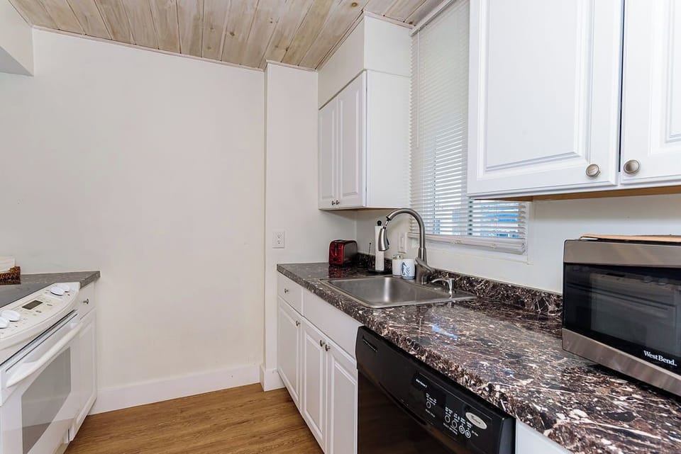 Bright galley kitchen with marble-look counters, dishwasher, and essentials.