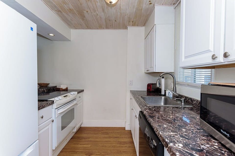 Cozy galley kitchen with marble-look tops and full appliances