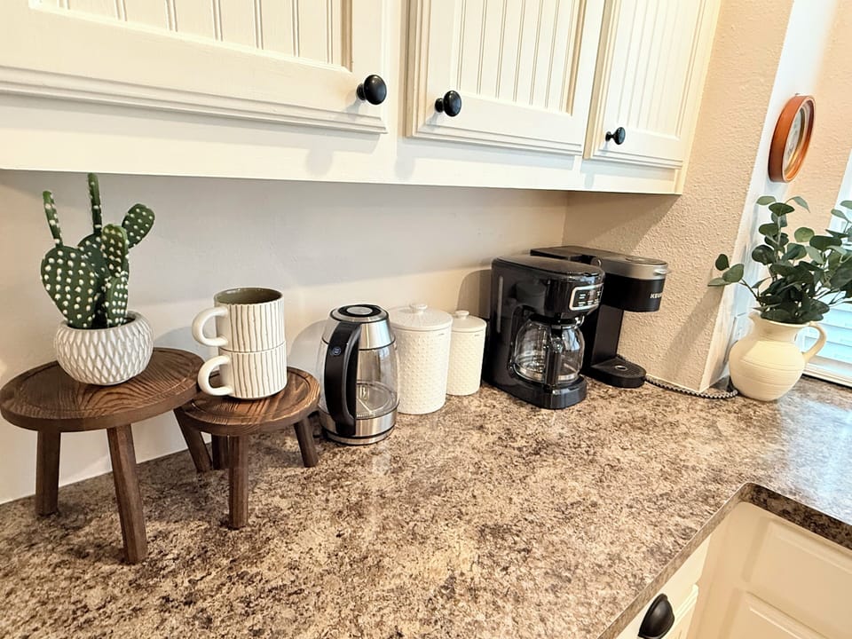 Coffee bar station is fully stocked with coffee beans, a grinder, sugar & kpods