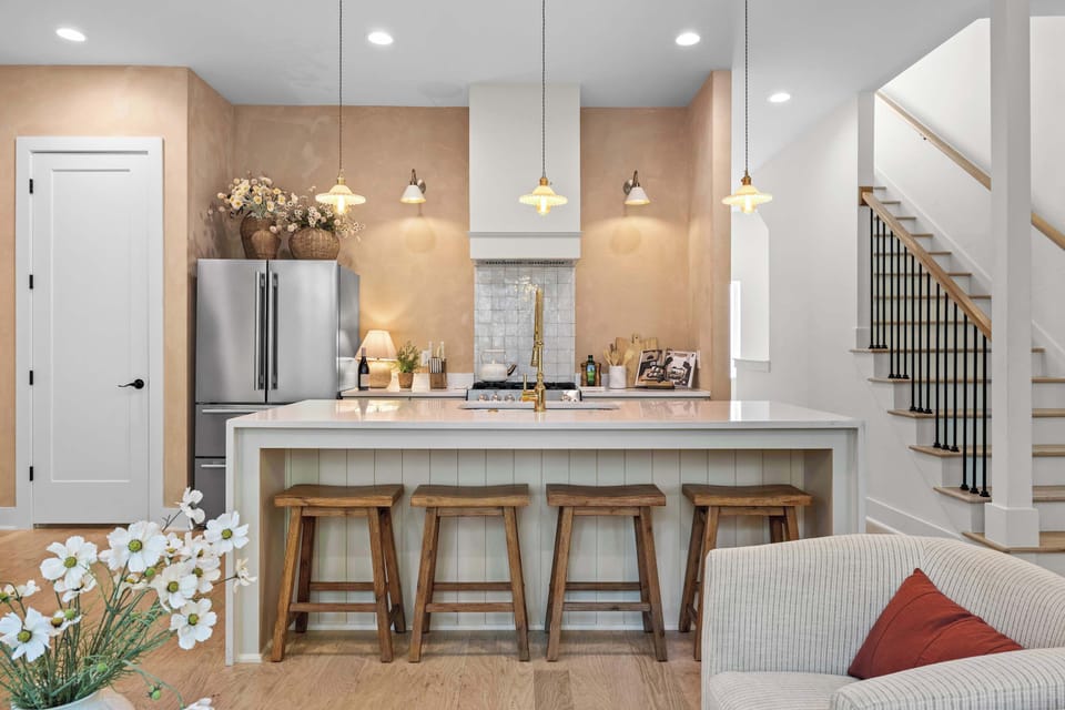 Kitchen island with quartz countertop, brass faucet, pendant lighting, and seating for four. 