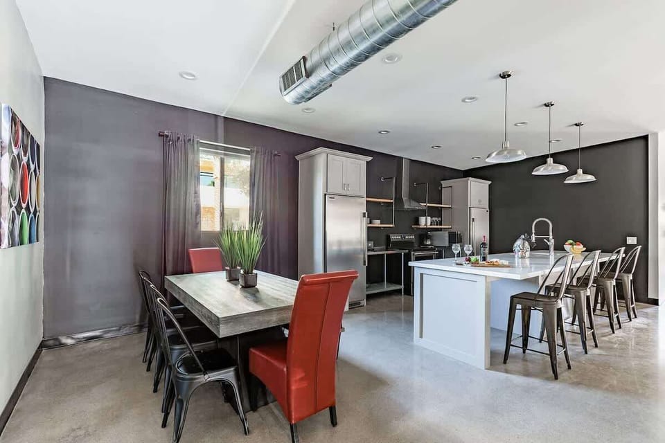 Fully equipped modern kitchen featuring stainless steel appliances, kitchen island with bar seating for 4 guests and a formal dining table with seating for 8 guests.