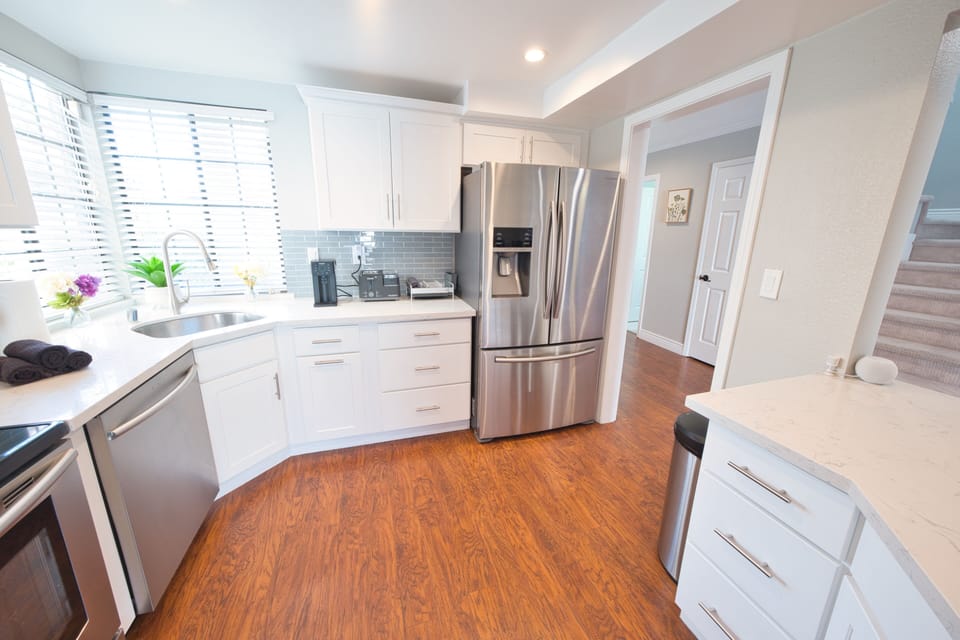 Bright quartz kitchen with SS appliances and sunny corner sink
