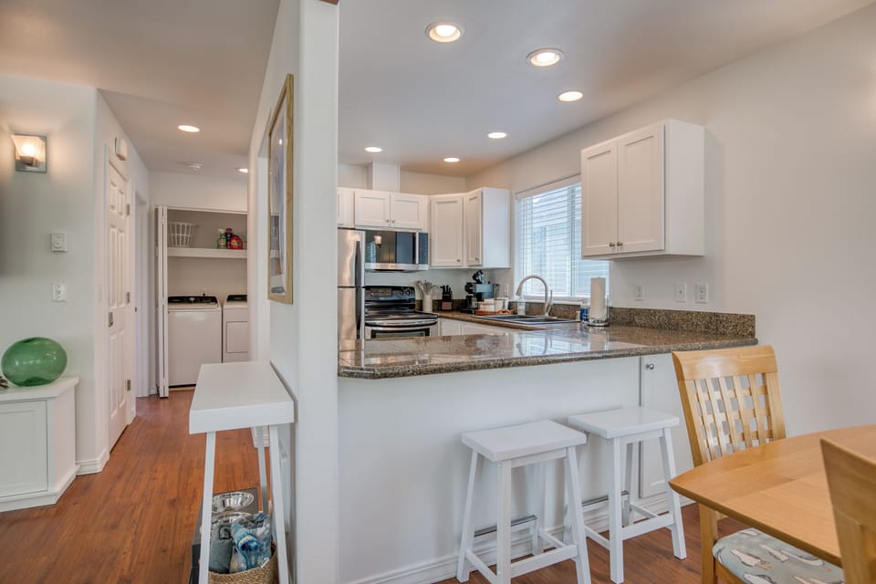 Bright and functional! This hallway connects the main living spaces and features a tucked-away laundry nook with a washer and dryer, providing all the conveniences of home during your stay.