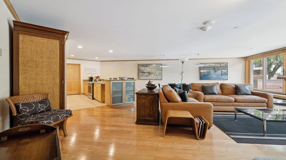Unwind in your spacious open-plan living area with warm wood floors, plush leather seating, and a fully equipped kitchen—perfect for relaxing after a day exploring the area.