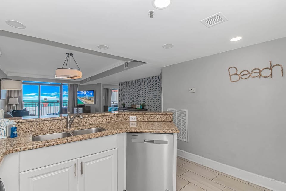 Bright, updated kitchen featuring granite countertops, stainless steel appliances, and an open layout overlooking the living room and ocean.